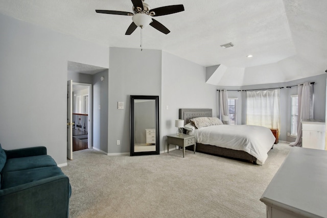 bedroom featuring ceiling fan, light colored carpet, visible vents, baseboards, and vaulted ceiling