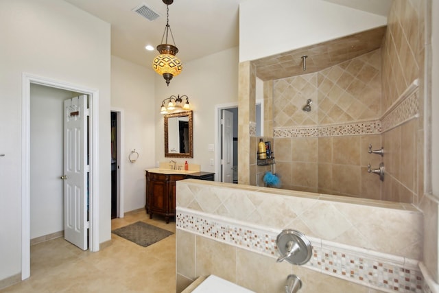 full bathroom featuring tiled shower, vanity, and visible vents