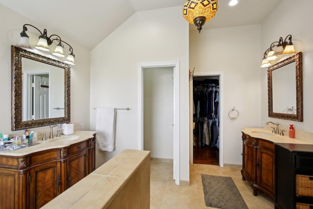 bathroom featuring two vanities, vaulted ceiling, and a sink