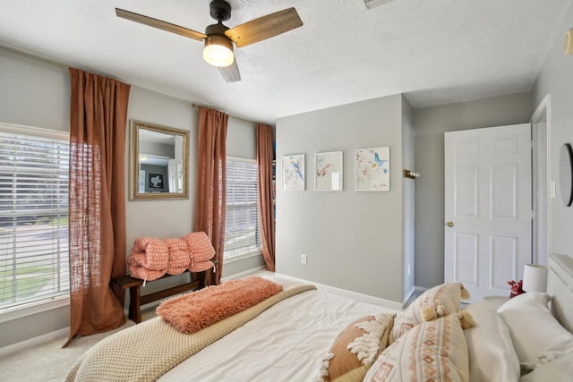 bedroom with light carpet, a ceiling fan, baseboards, and a textured ceiling