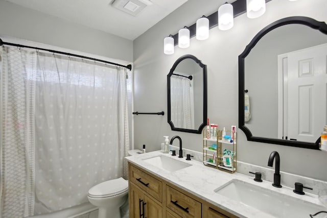 full bath with toilet, double vanity, visible vents, and a sink