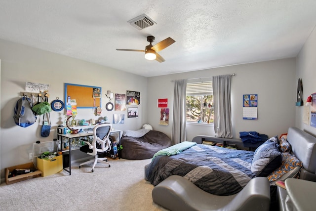 bedroom featuring carpet, a textured ceiling, visible vents, and a ceiling fan