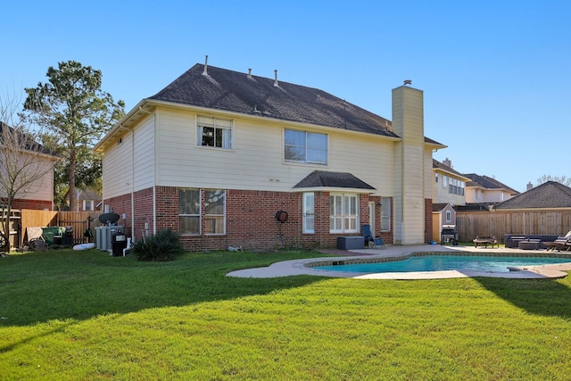 back of property with brick siding, a lawn, and a fenced backyard