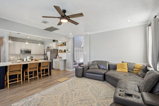 living area with a ceiling fan, visible vents, light wood-style flooring, and stairs