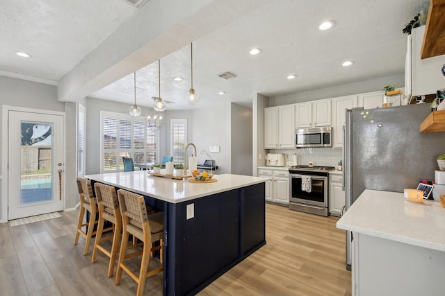 kitchen featuring stainless steel appliances, visible vents, white cabinets, light wood-type flooring, and tasteful backsplash