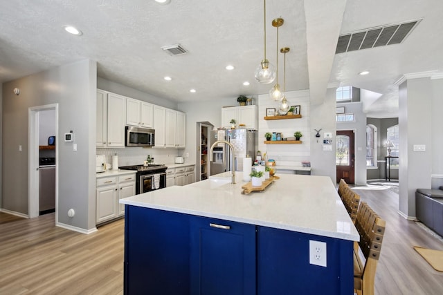 kitchen featuring visible vents, light wood-style flooring, appliances with stainless steel finishes, white cabinetry, and a sink