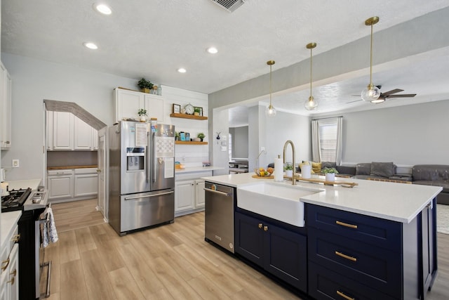 kitchen with stainless steel appliances, light countertops, a sink, and white cabinetry