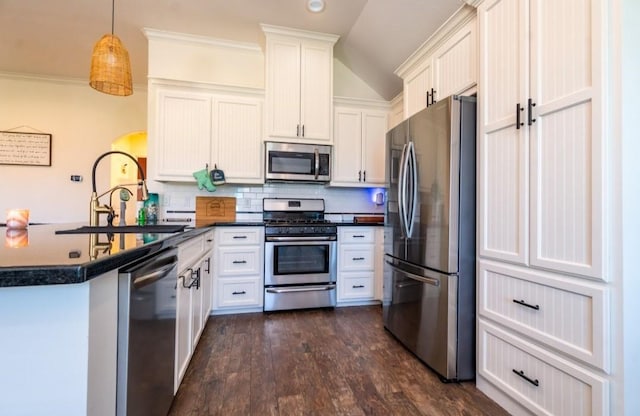 kitchen featuring dark countertops, decorative backsplash, appliances with stainless steel finishes, dark wood-type flooring, and a sink