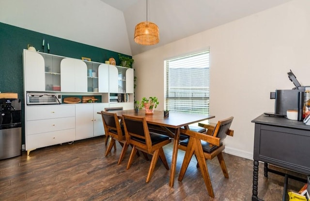 dining room featuring dark wood-type flooring, lofted ceiling, and baseboards