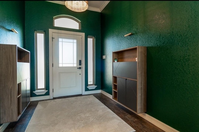 doorway to outside featuring baseboards, a textured wall, wood finished floors, and crown molding