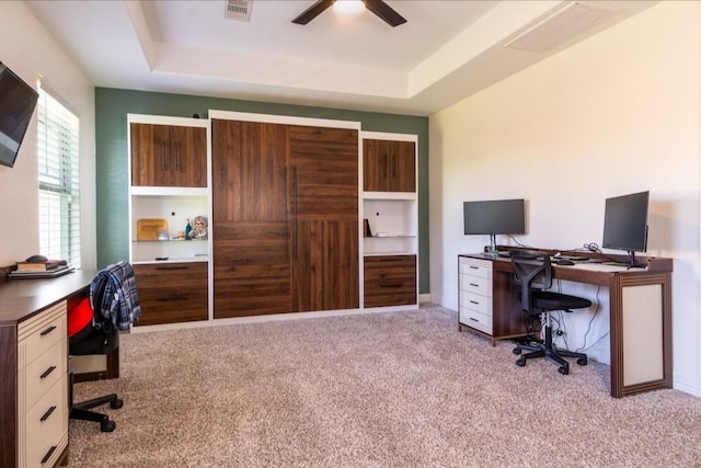 office featuring ceiling fan, carpet floors, a raised ceiling, and visible vents