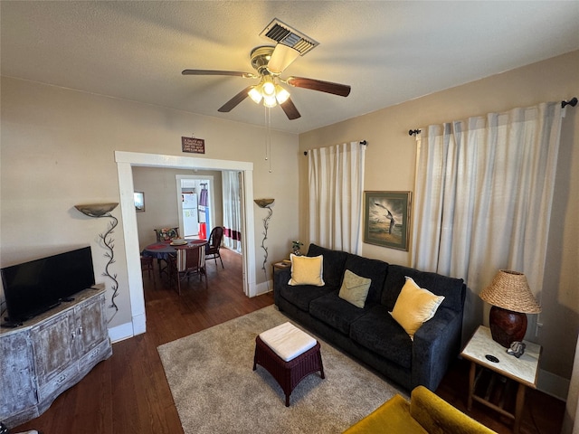 living area featuring baseboards, a textured ceiling, a ceiling fan, and wood finished floors