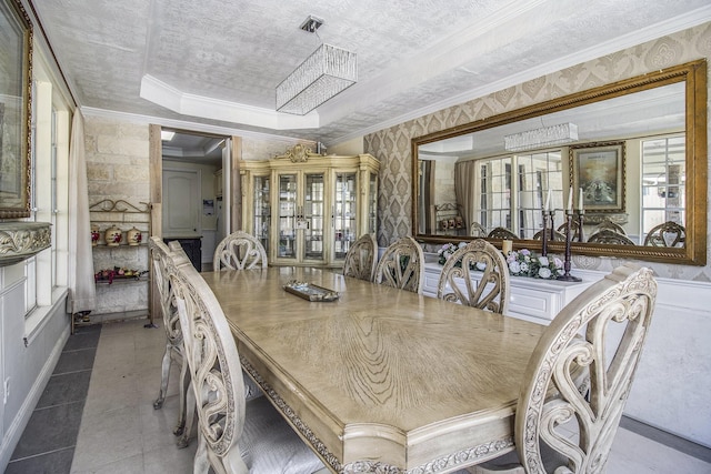 tiled dining room featuring ornamental molding, a wealth of natural light, a raised ceiling, and a textured ceiling