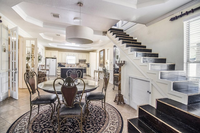 dining room featuring ornamental molding, a raised ceiling, visible vents, and stairs