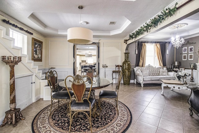 tiled dining room with a textured ceiling, a notable chandelier, visible vents, a raised ceiling, and crown molding