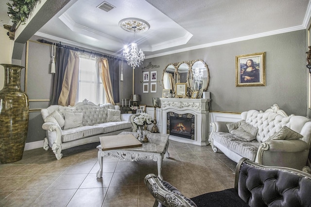 living area featuring a chandelier, tile patterned flooring, visible vents, a lit fireplace, and a tray ceiling