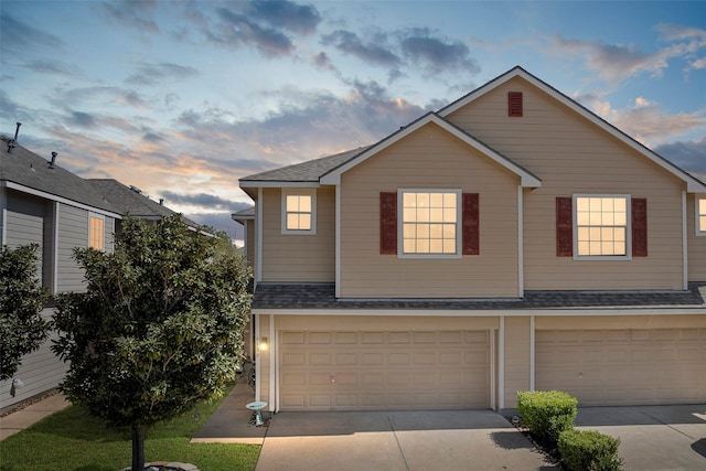 view of front of home with a shingled roof, concrete driveway, and an attached garage