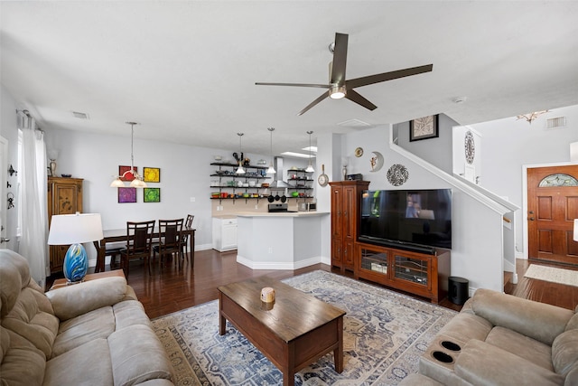 living room featuring dark wood-style floors, ceiling fan, visible vents, and baseboards