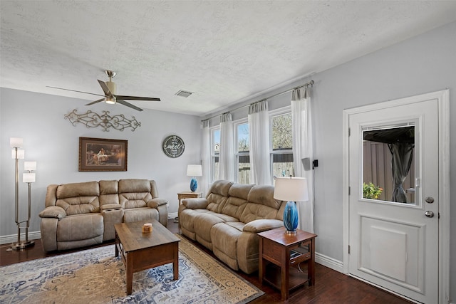 living room with baseboards, a textured ceiling, visible vents, and dark wood-style flooring