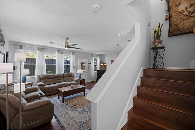 living room with visible vents, stairway, dark wood-type flooring, ceiling fan, and baseboards