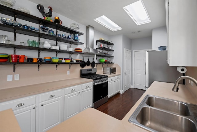 kitchen with open shelves, stainless steel appliances, white cabinets, a sink, and wall chimney range hood