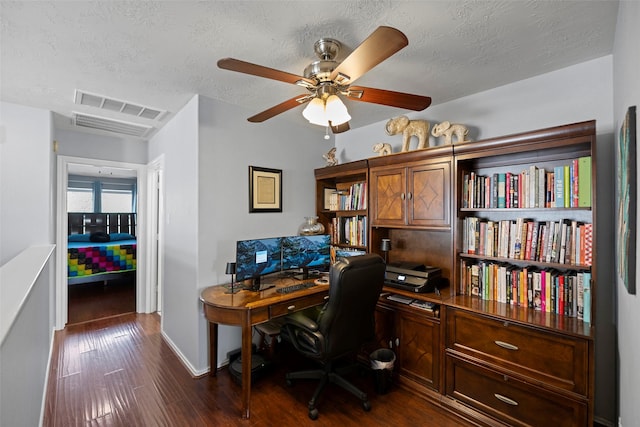 office space with ceiling fan, a textured ceiling, dark wood-type flooring, visible vents, and baseboards