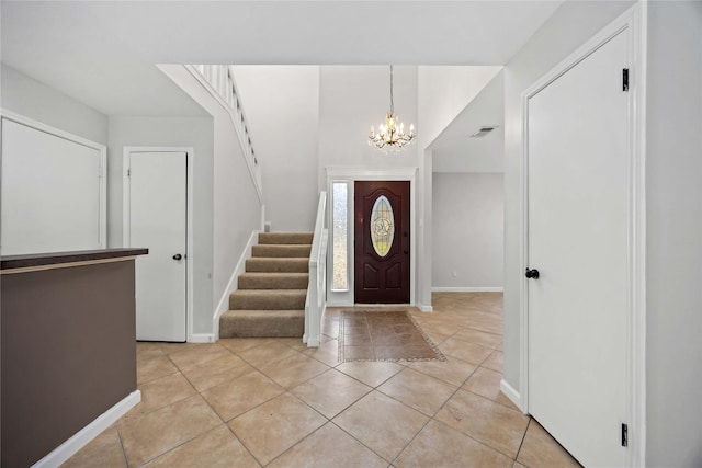 foyer entrance with a notable chandelier, light tile patterned floors, visible vents, baseboards, and stairs