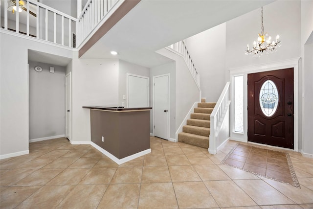 entryway with baseboards, a chandelier, a towering ceiling, and tile patterned floors