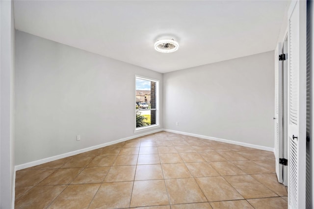 empty room featuring light tile patterned flooring and baseboards