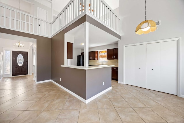 entryway with a notable chandelier, light tile patterned floors, visible vents, a high ceiling, and baseboards