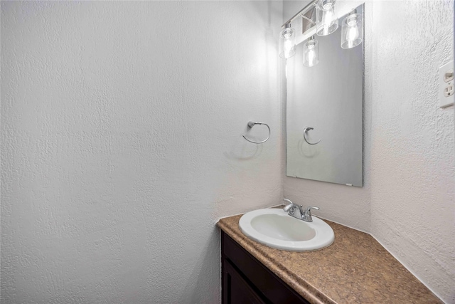 bathroom with a textured wall and vanity