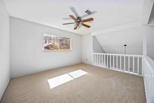 carpeted spare room with lofted ceiling, visible vents, and a ceiling fan