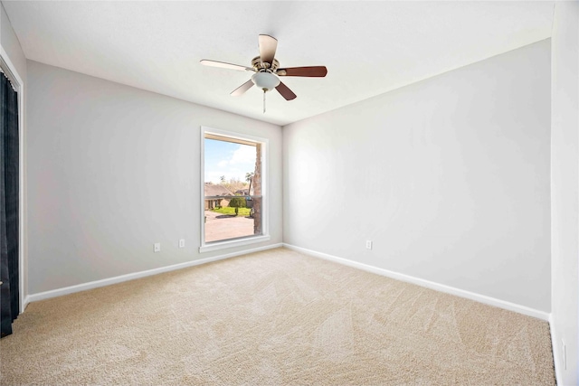 carpeted empty room with ceiling fan and baseboards