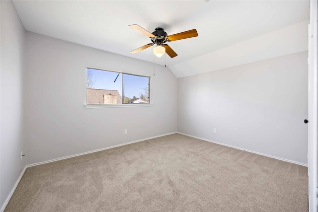 carpeted empty room featuring lofted ceiling, baseboards, and a ceiling fan