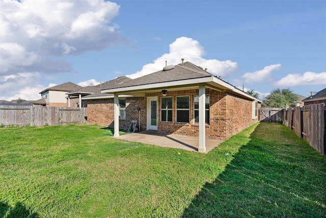 back of house featuring a yard, a patio, brick siding, and a fenced backyard