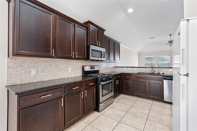 kitchen featuring stainless steel appliances, lofted ceiling, light tile patterned flooring, a sink, and dark brown cabinetry