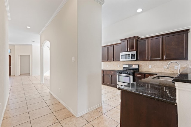 kitchen with light tile patterned floors, decorative backsplash, dark stone counters, appliances with stainless steel finishes, and a sink