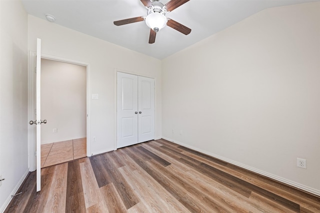 unfurnished bedroom featuring a closet, ceiling fan, baseboards, and wood finished floors