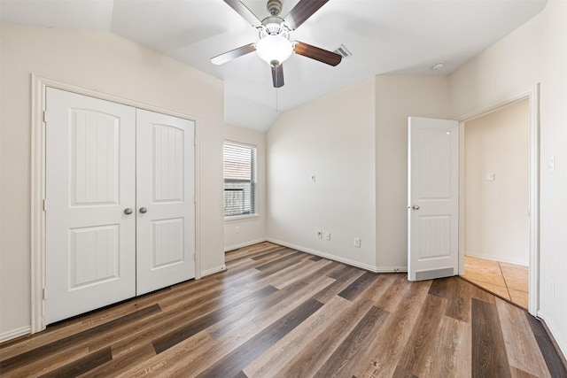 unfurnished bedroom featuring lofted ceiling, a closet, a ceiling fan, and wood finished floors