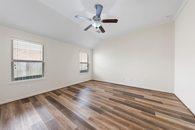 empty room featuring lofted ceiling, ornamental molding, a ceiling fan, wood finished floors, and baseboards