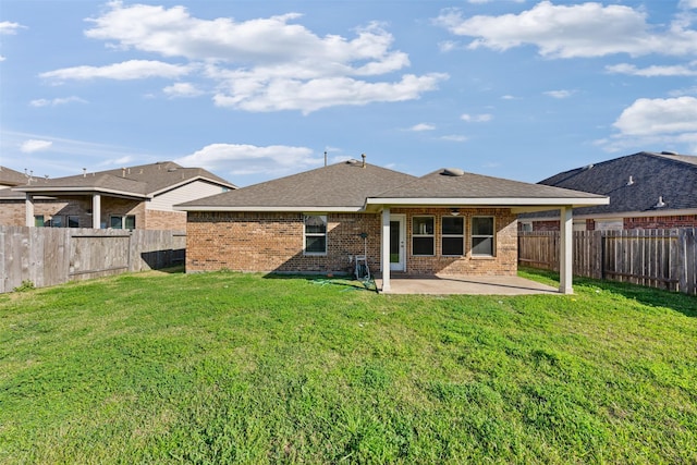 back of property with a shingled roof, a lawn, a patio, a fenced backyard, and brick siding