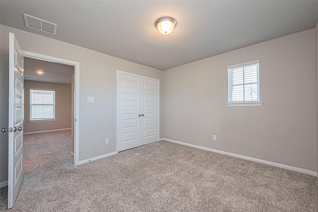 unfurnished bedroom featuring a closet, baseboards, visible vents, and carpet floors