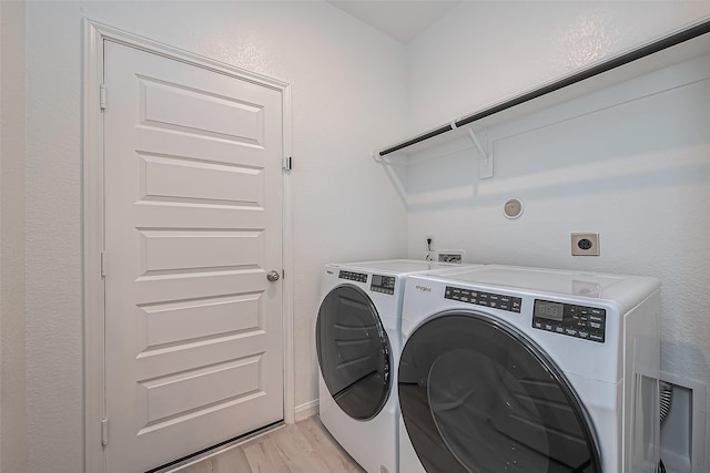 laundry area featuring laundry area, light wood-style floors, and washer and clothes dryer