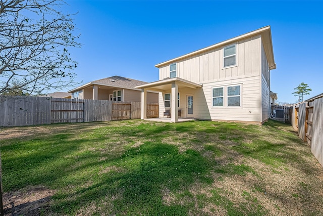 rear view of property with a patio area, a lawn, board and batten siding, and a fenced backyard