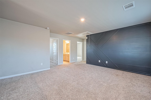 unfurnished room with visible vents, light colored carpet, attic access, and baseboards