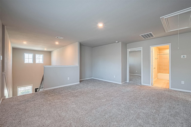 unfurnished room featuring visible vents, baseboards, attic access, and carpet flooring