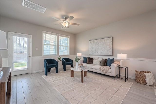 living area with light wood-type flooring, baseboards, visible vents, and ceiling fan