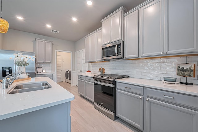 kitchen featuring visible vents, a sink, gray cabinetry, light countertops, and stainless steel appliances