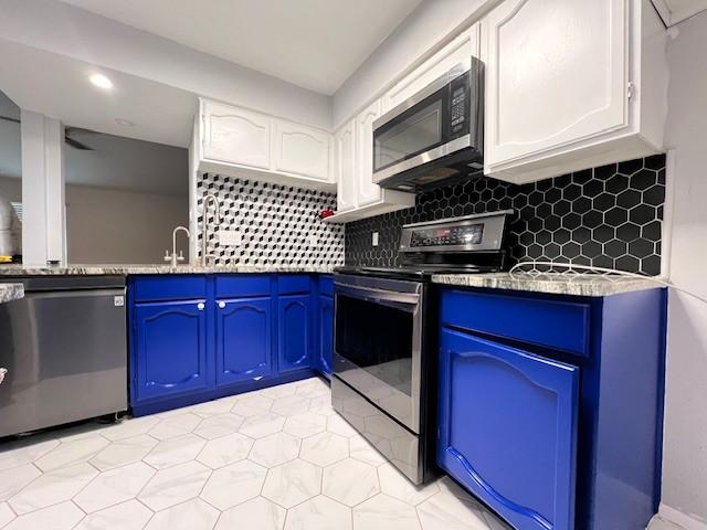 kitchen featuring blue cabinets, appliances with stainless steel finishes, backsplash, and white cabinets