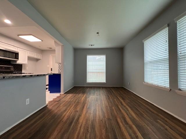 unfurnished living room with baseboards and dark wood-style flooring